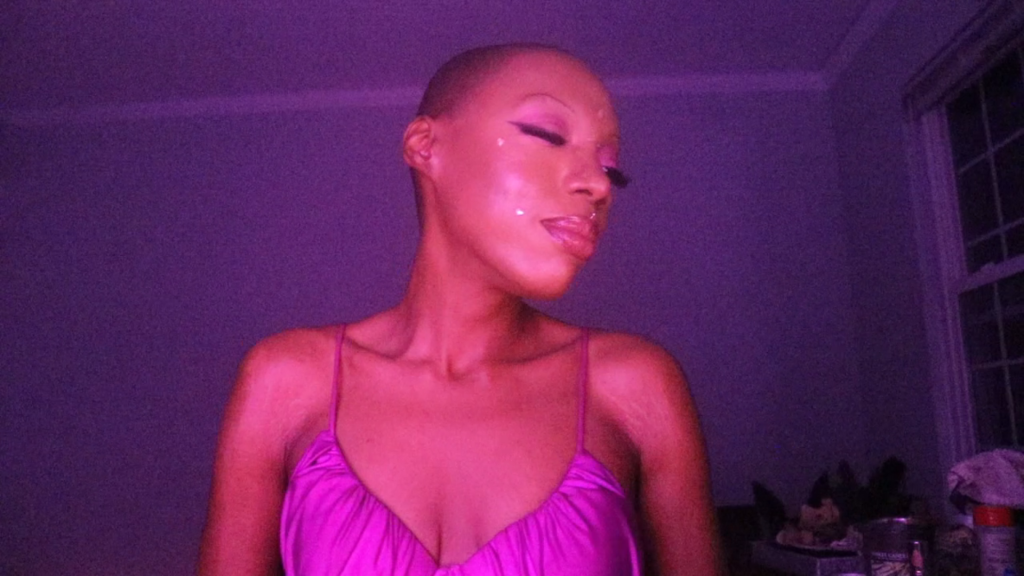 Black Findom Goddess Candy Divine wearing purple lingerie, her cleavage front and center, with a gorgeous shaved head and her eyes closed, relishing in all of the cash her Good Ones, like you, sent her.